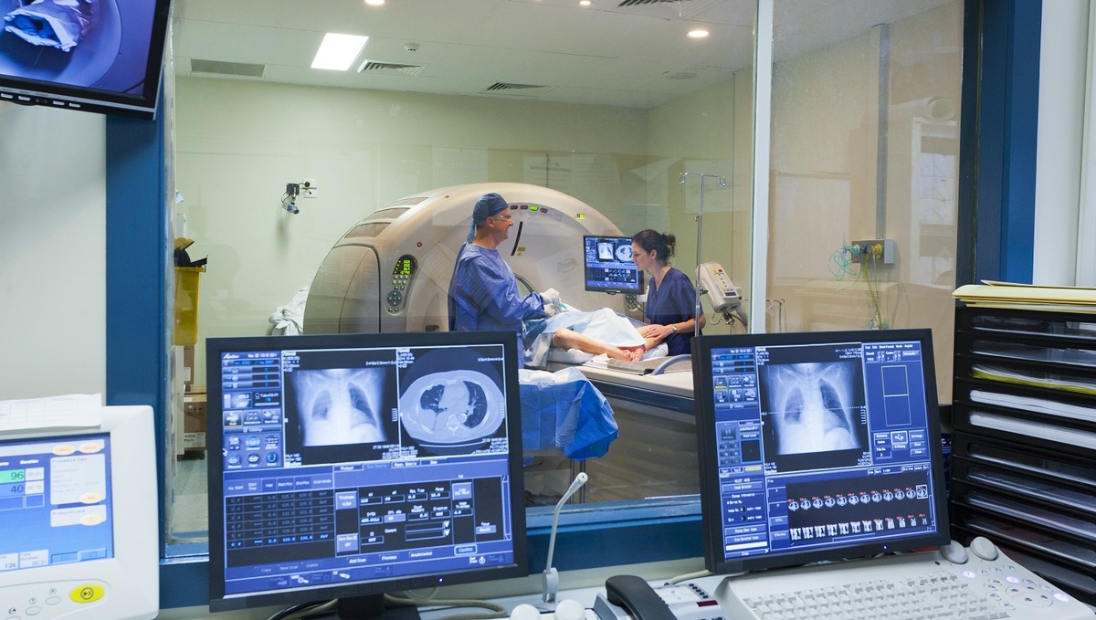 medical team preforming procedure and scans on screen